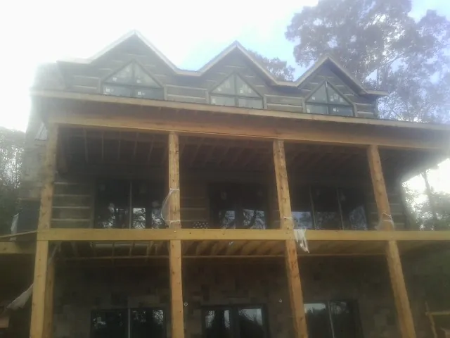 Dormers and porch framing on a large log home under construction — Roof Coating work by our crew in Bretz
