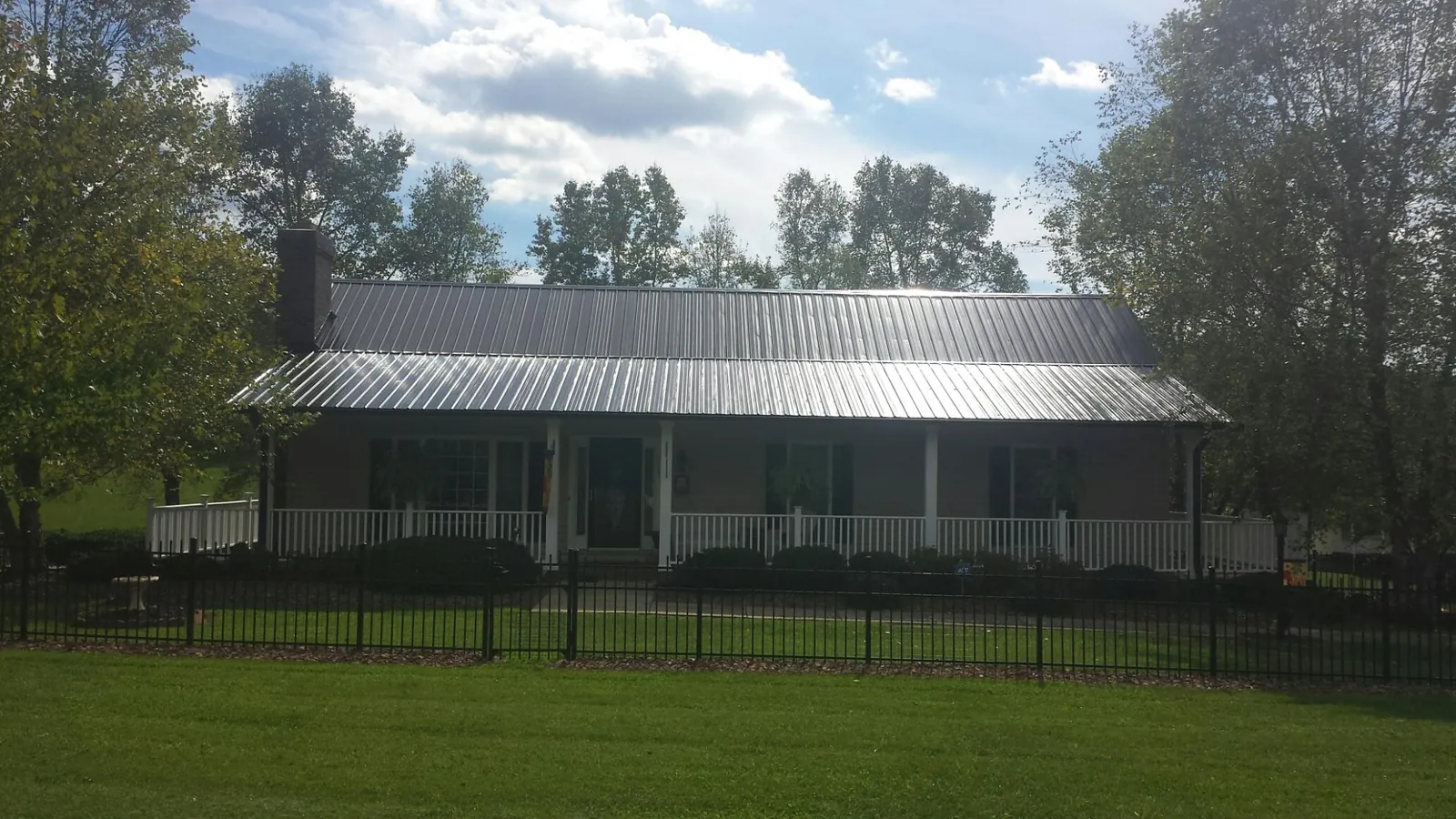 Gray metal roof on a brick ranch with a full width front porch — Gutter Guard Installation work by our crew in Bretz