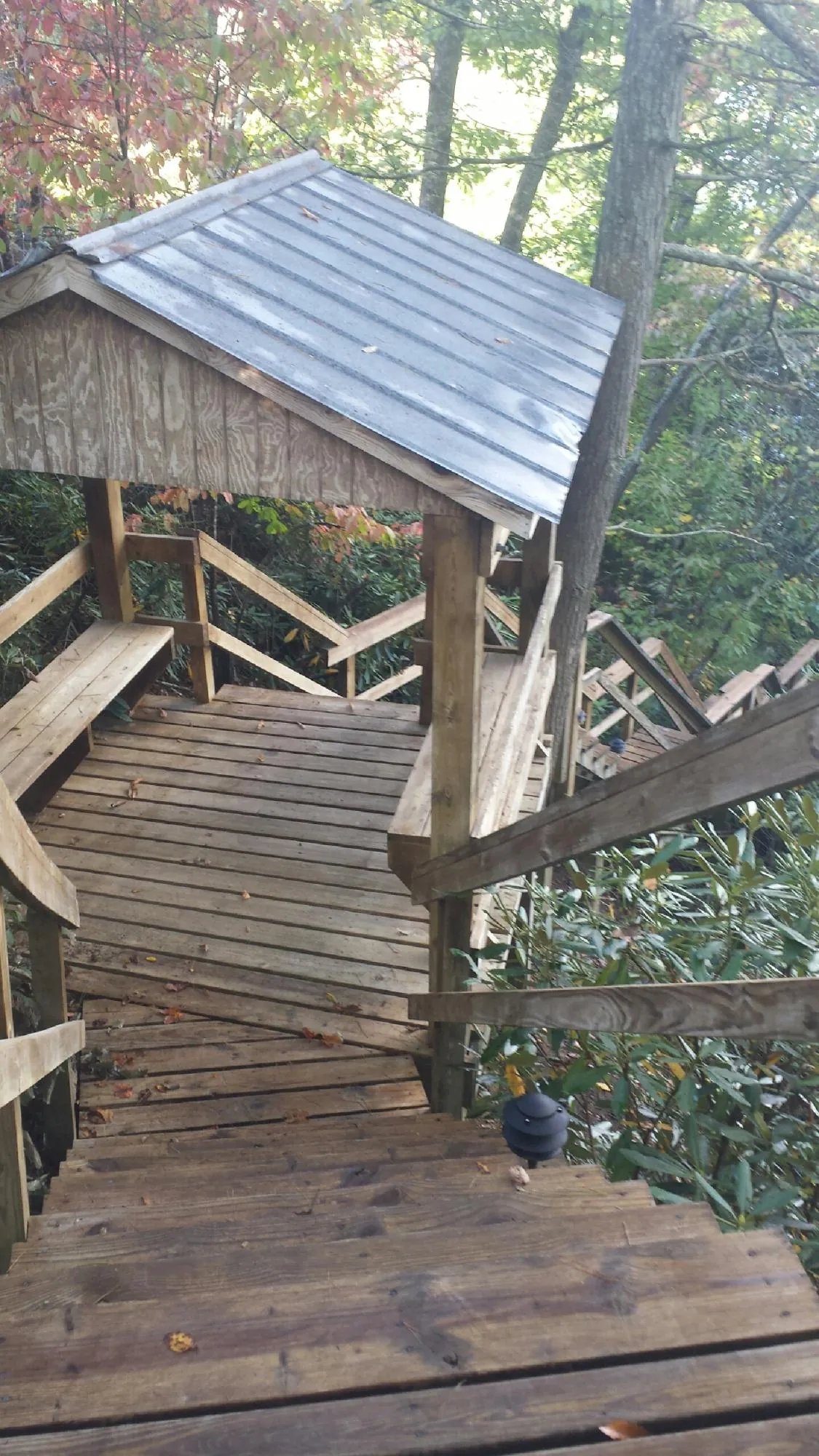Metal roofed shelter over wooden steps on a wooded walkway — Skylight Repair & Installation work by our crew in Bretz