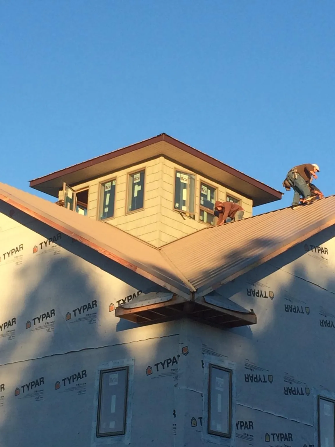 Roofers working around a rooftop cupola on a new metal roof at sunset — Roof Waterproofing in Bretz by Roofing Brothers
